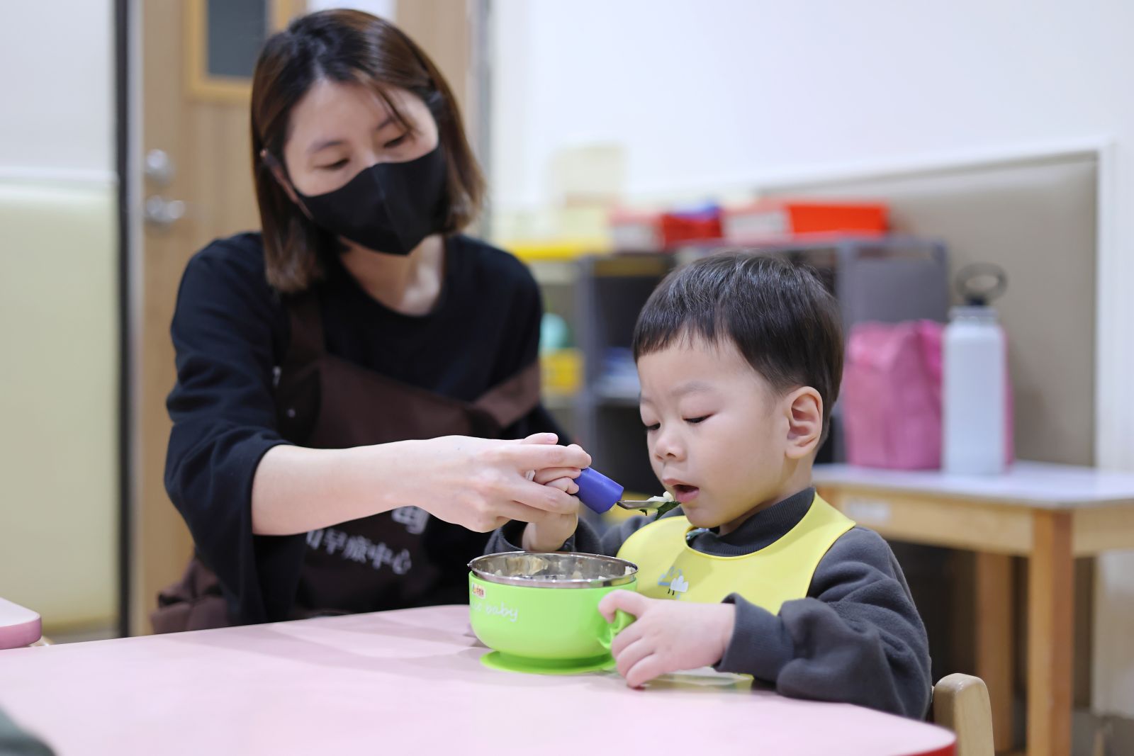在老師引導下用湯匙一口一口把飯送進嘴裡。